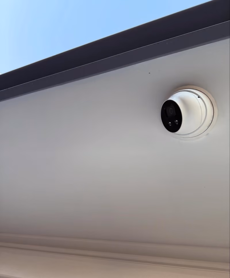 Hikvision camera installed under the eave of a two-storey building.